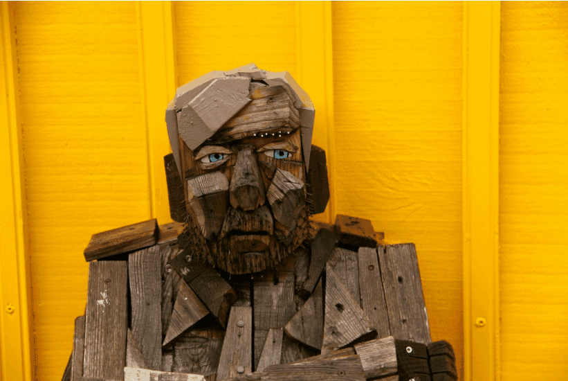 A sad looking man made out of lots of pieces of wood