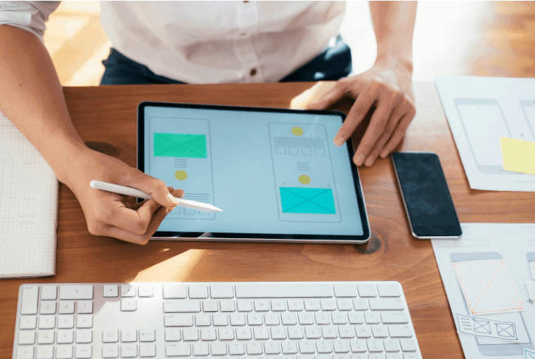 A web designer works on a tablet designing two versions of their homepage