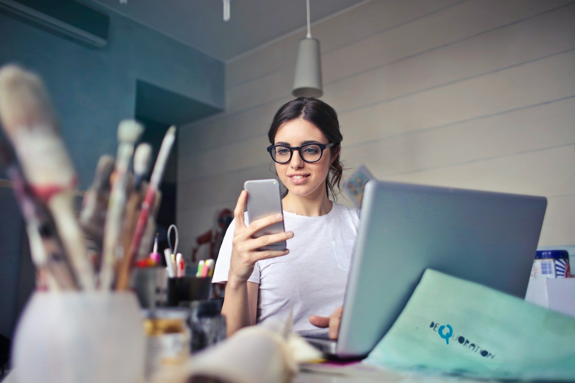 A woman running a small business smiles while using her smartphone
