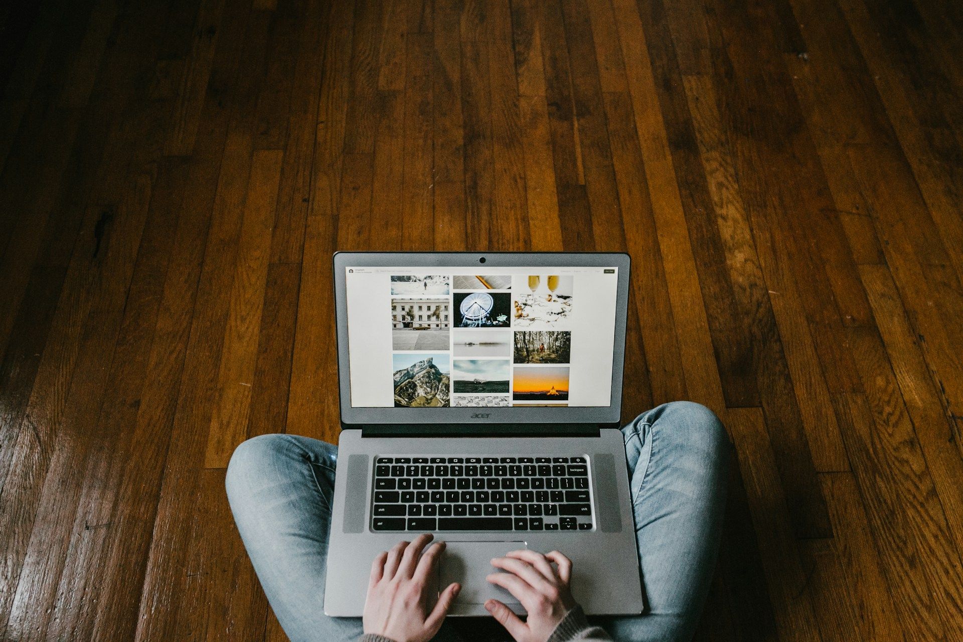 A woman sits on a wooden floor using a laptop to work on her business