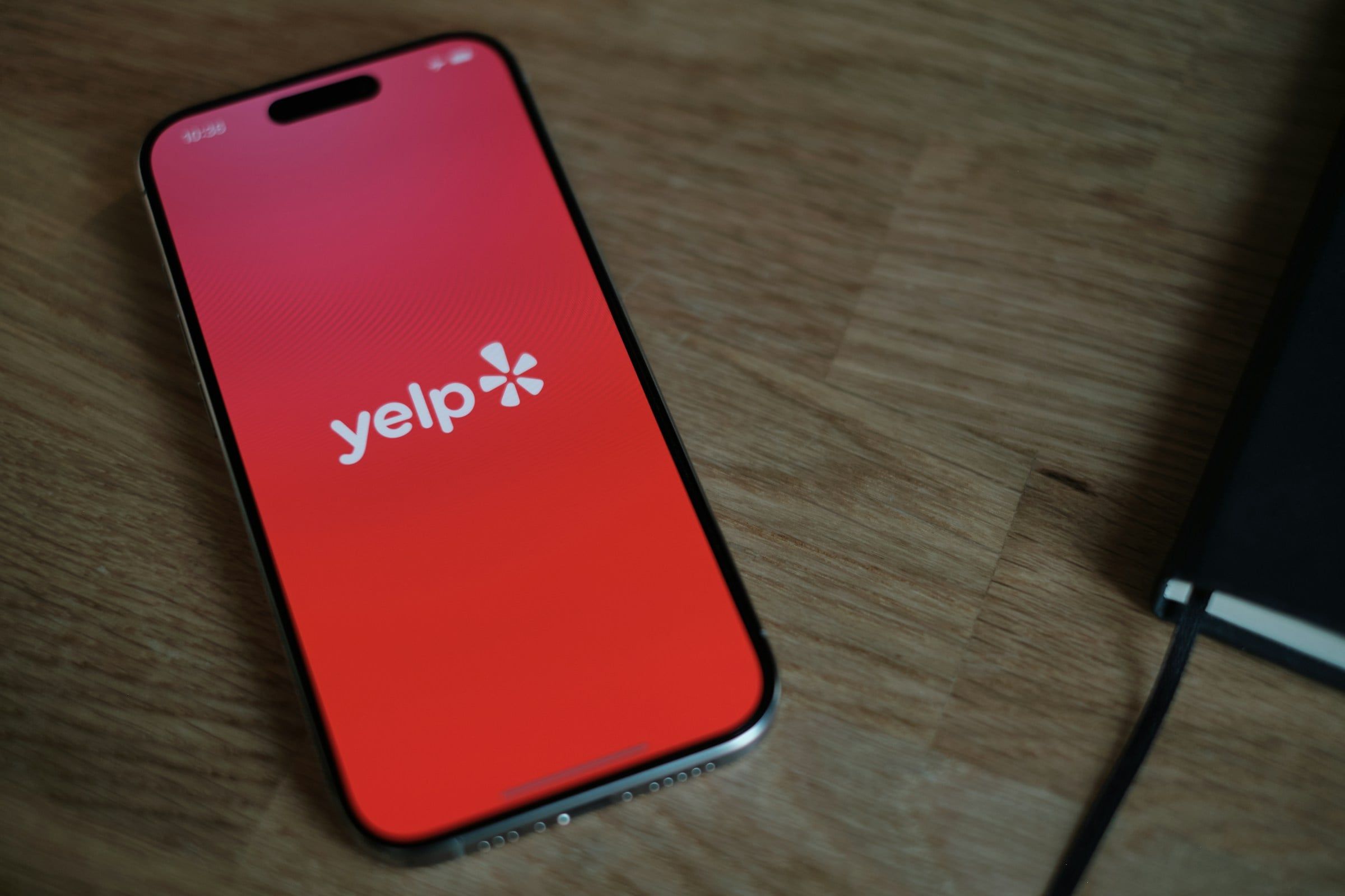 A smartphone on a desk with a large Yelp logo screen