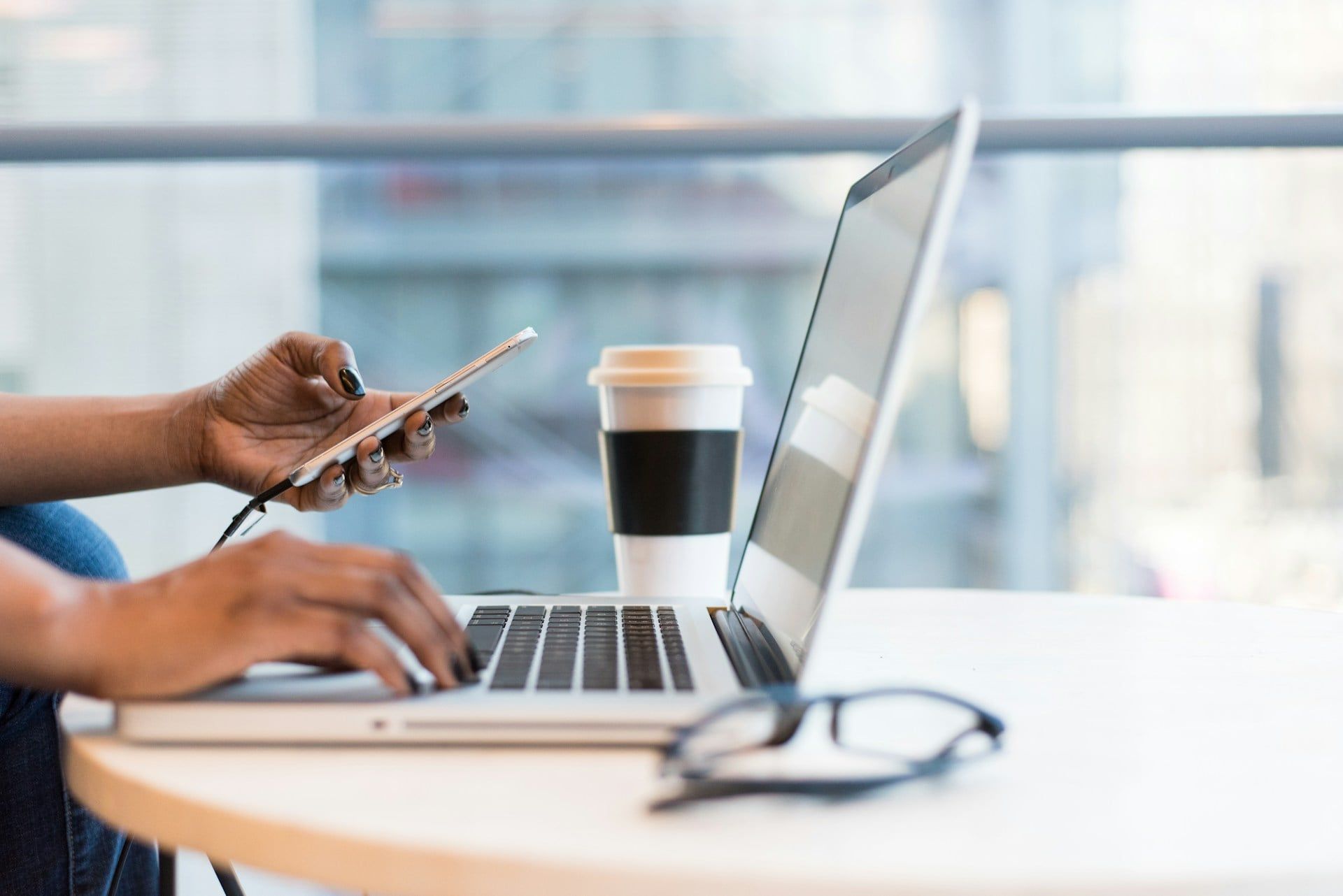 A close-up of someone using a laptop and smartphone to conduct business activities