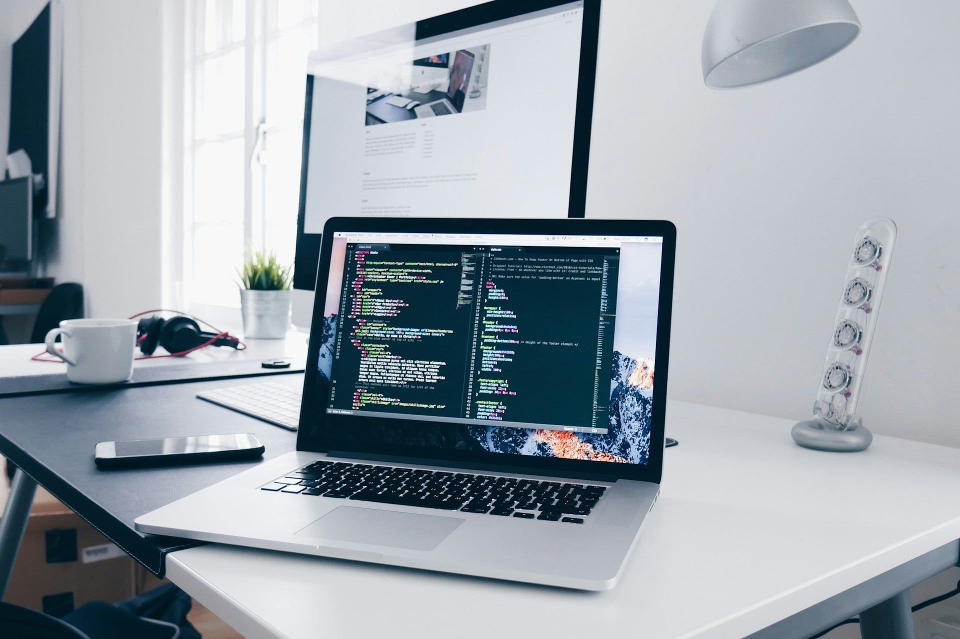An open laptop on a desk with website code on the screen