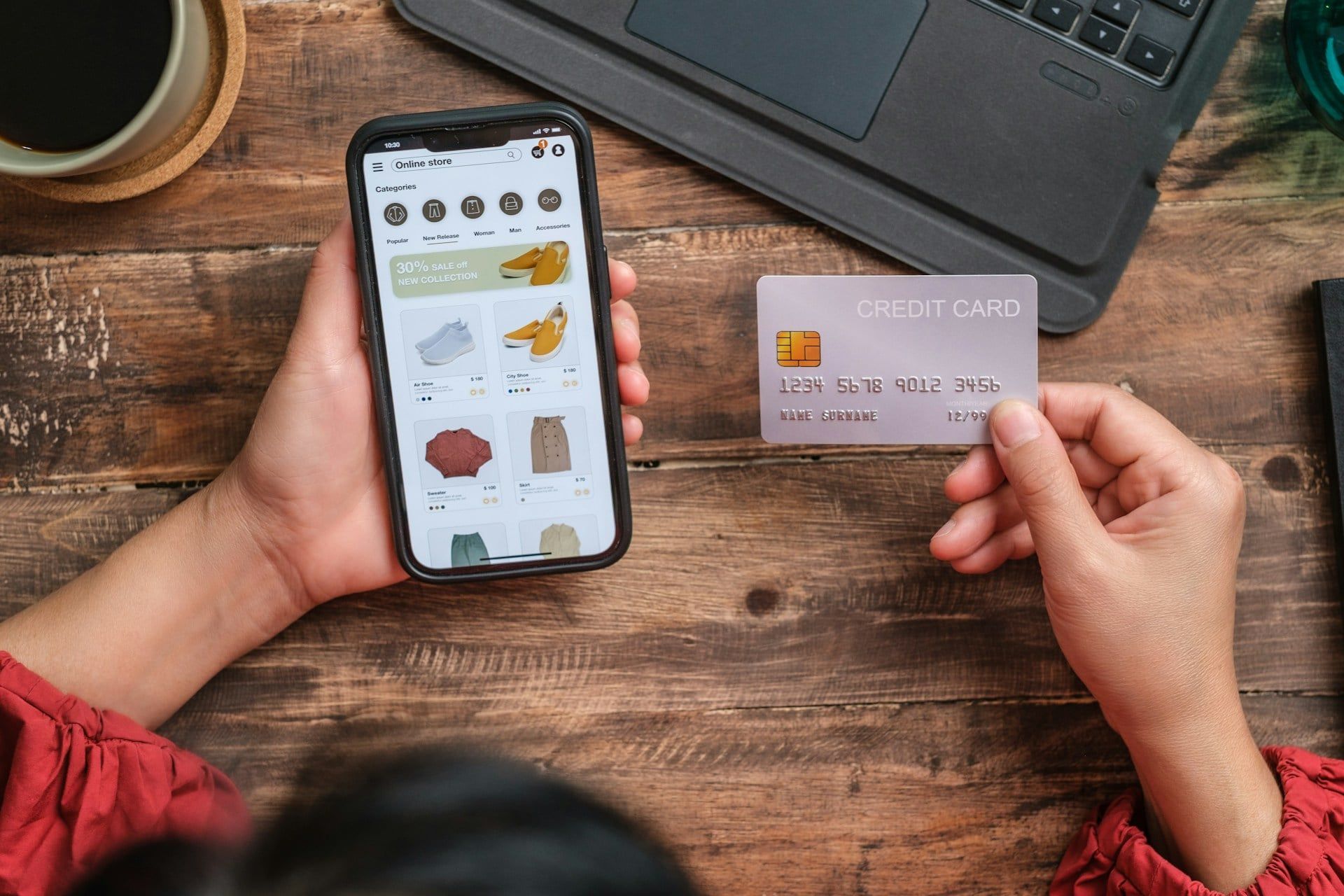 A held smartphone on an online store and credit card representing e-commerce activity