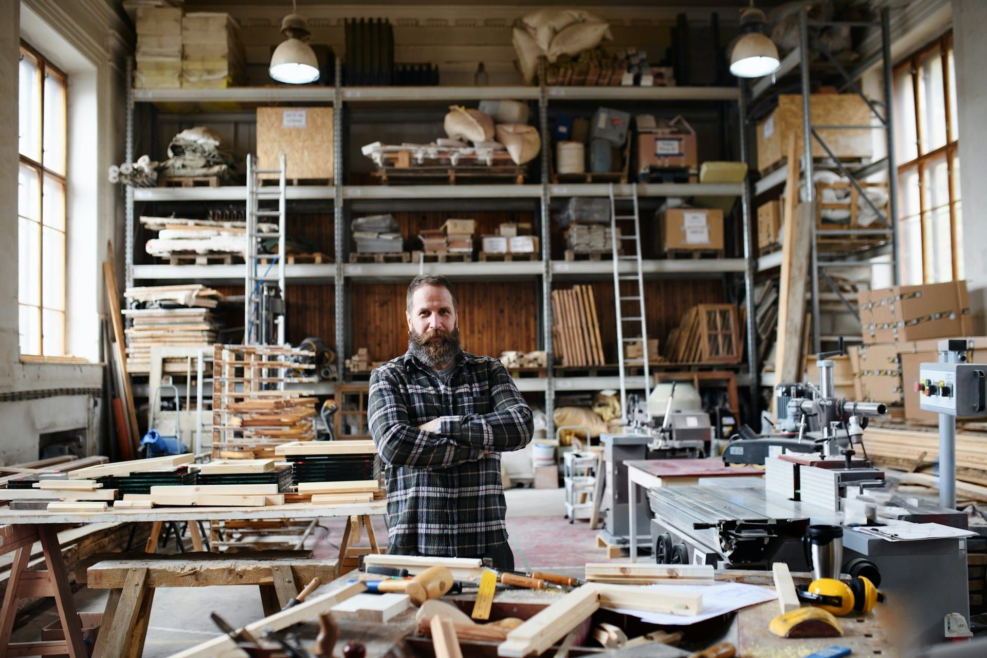 A creative male business owner standing with his arms folded in his workshop studio