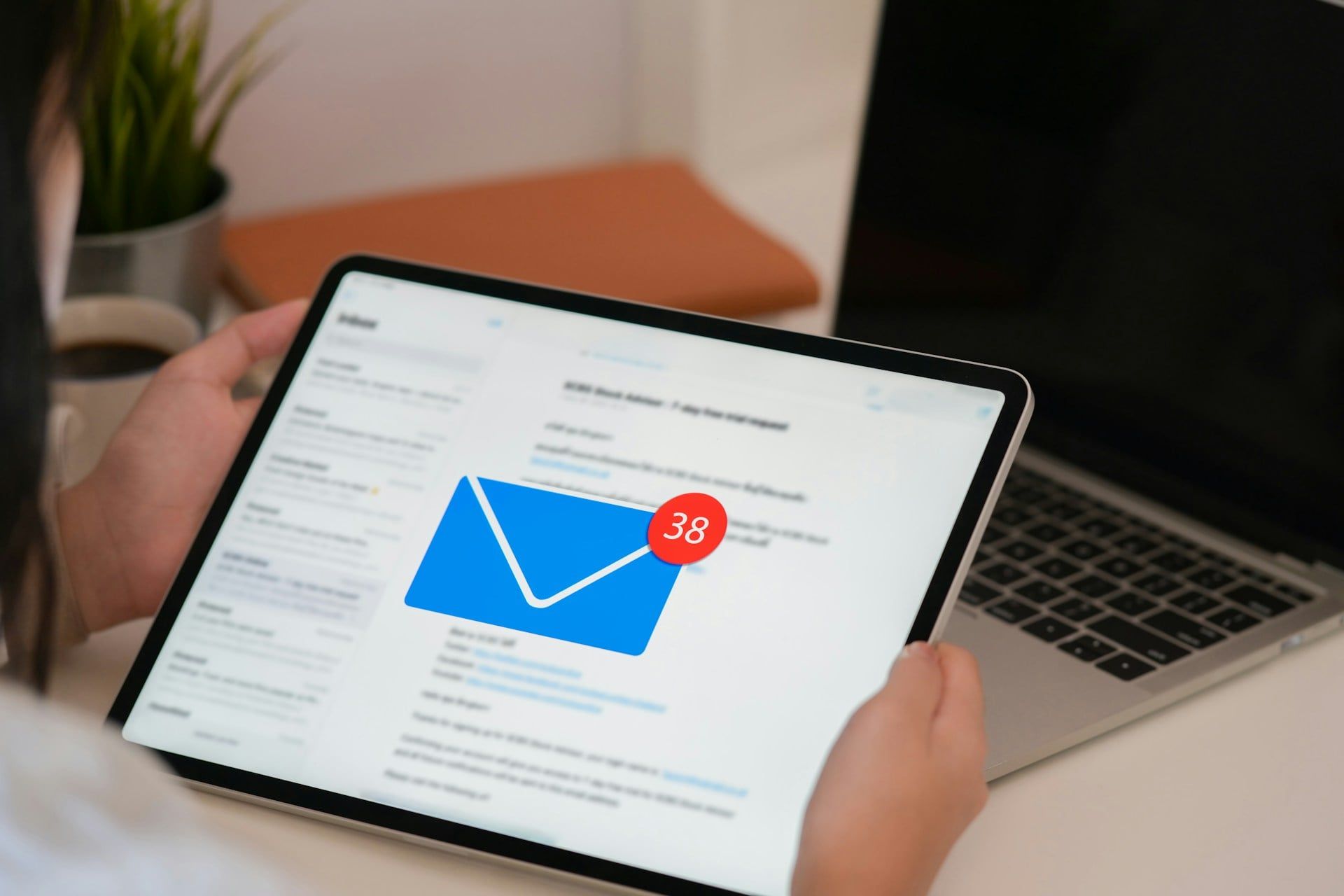 A graphic of someone holding a tablet with a large email notification in the center of the screen