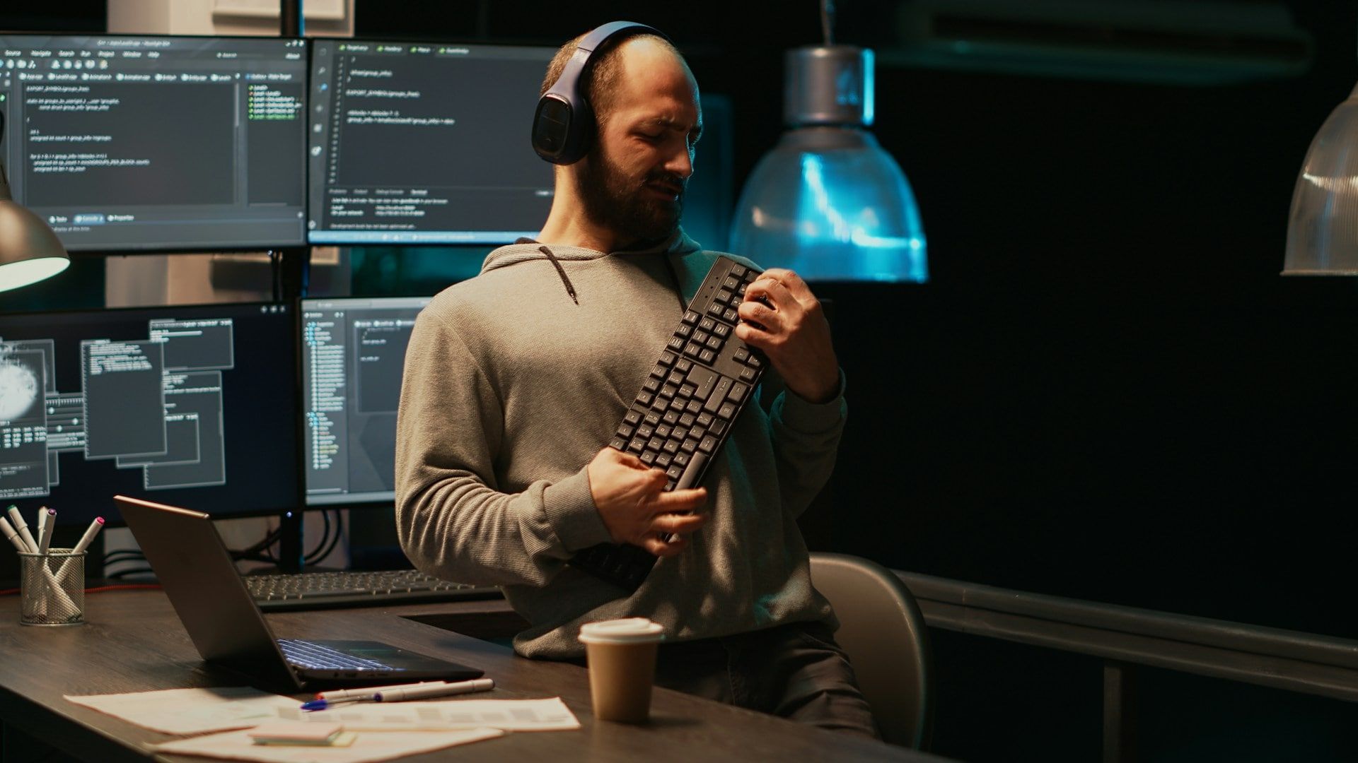 A man using a computer keyboard as a guitar while programming a website