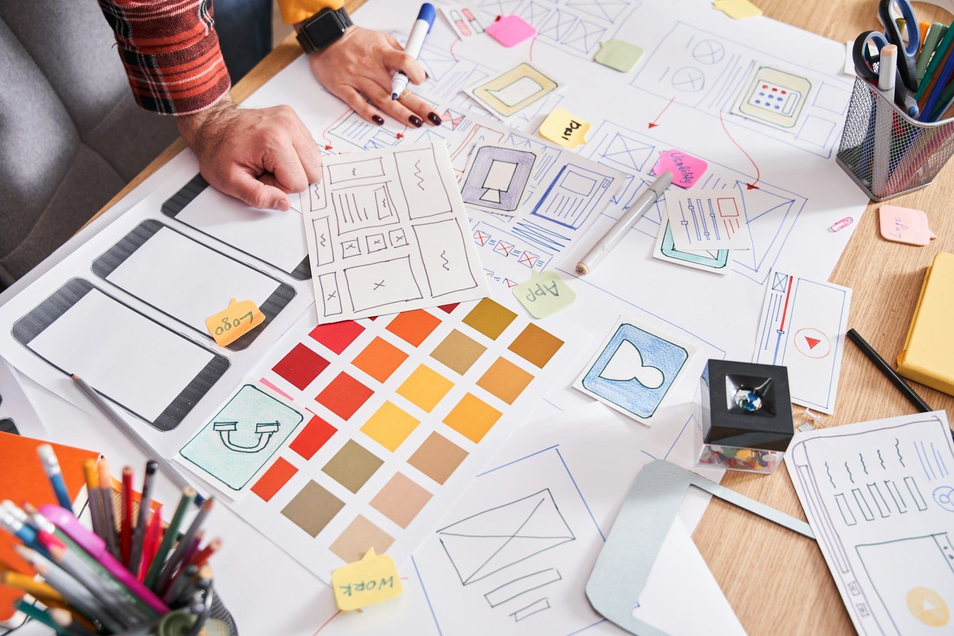 A workspace filled with papers and UX design ideas for a website and app