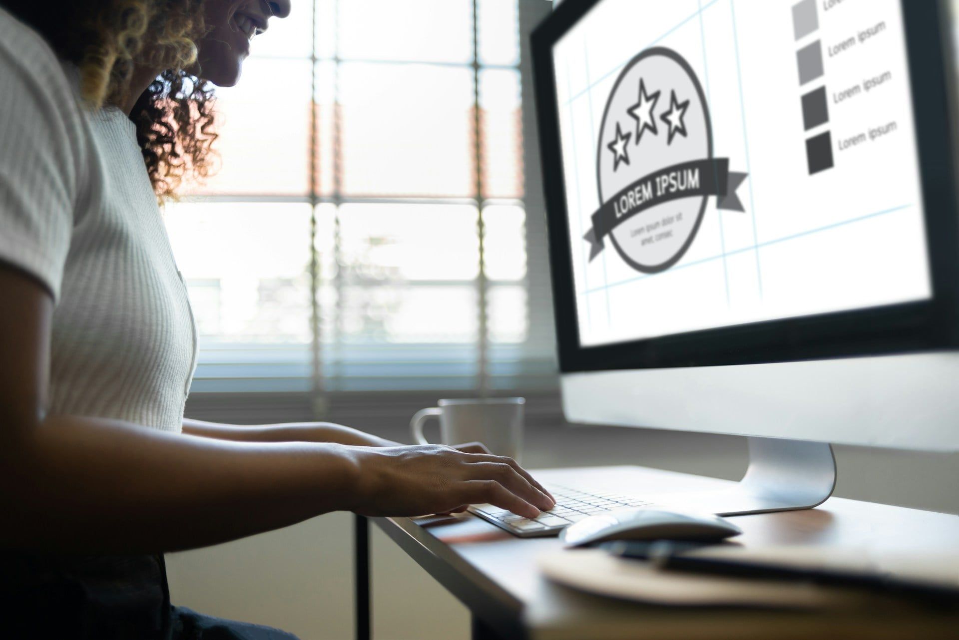 A lady working at a desktop computer to design her business’s website