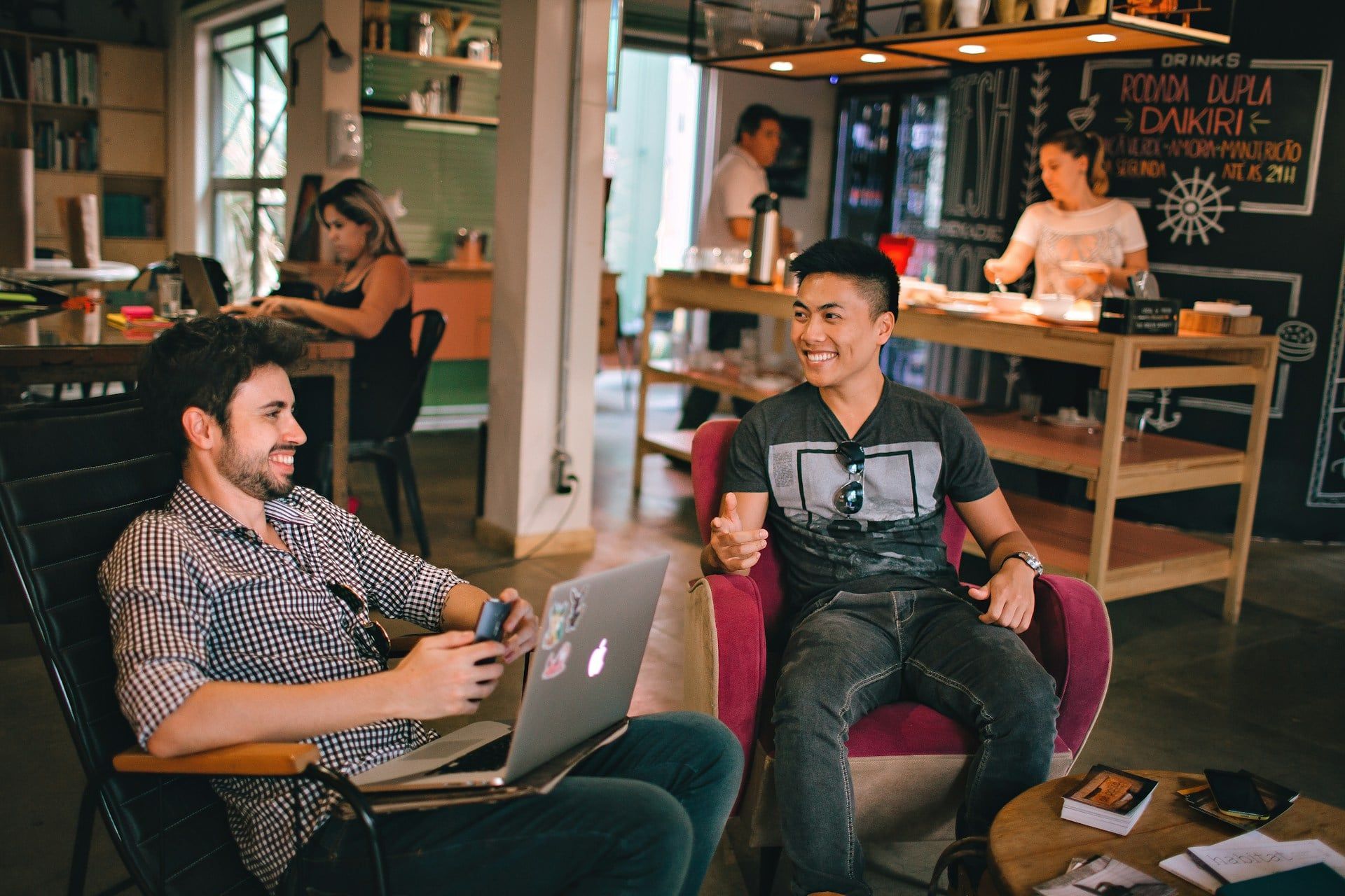 Two guys networking and building a relationship with each other in a cafe on bean bags with laptops