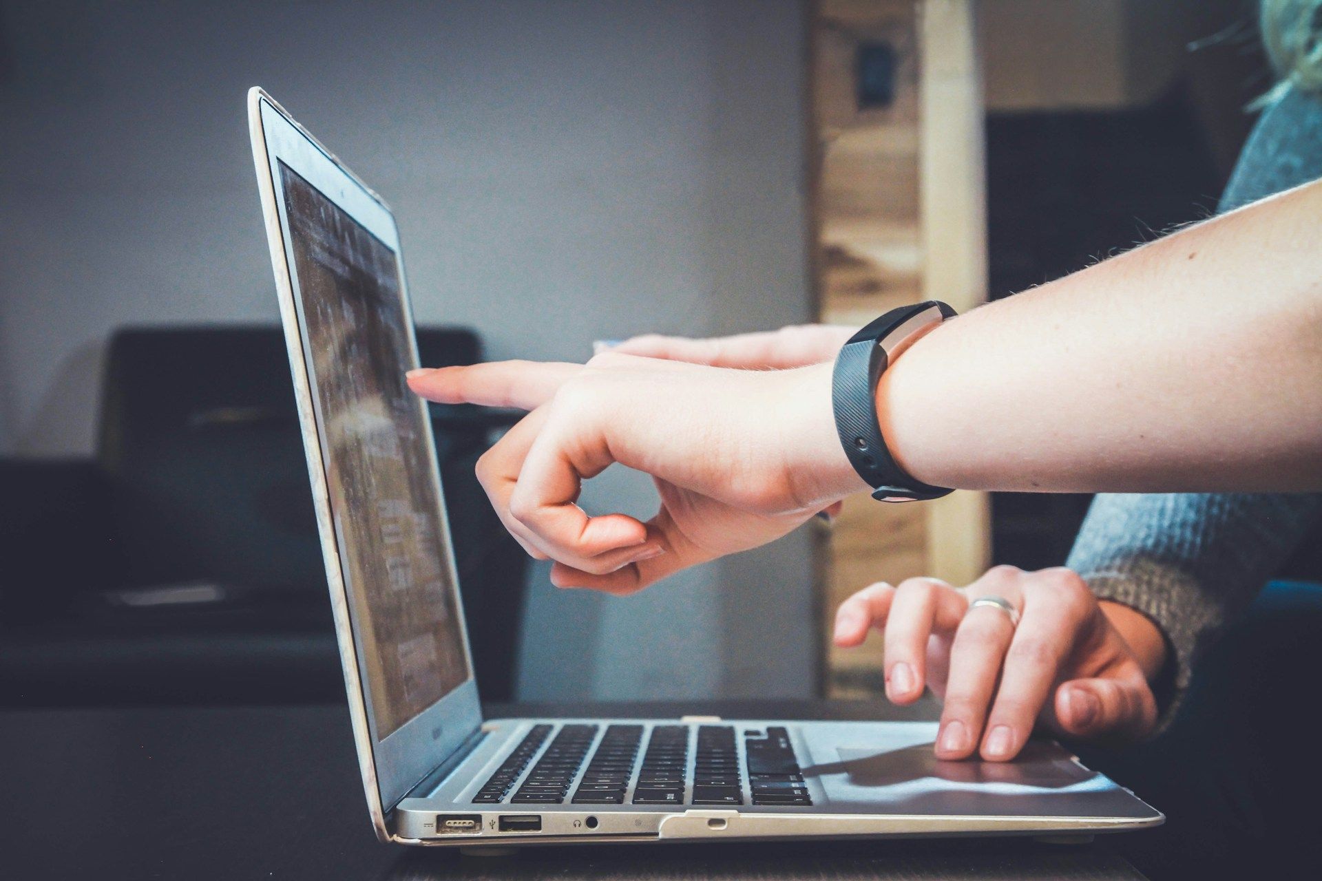 Two people working on a laptop and pointing to something in the middle of the screen