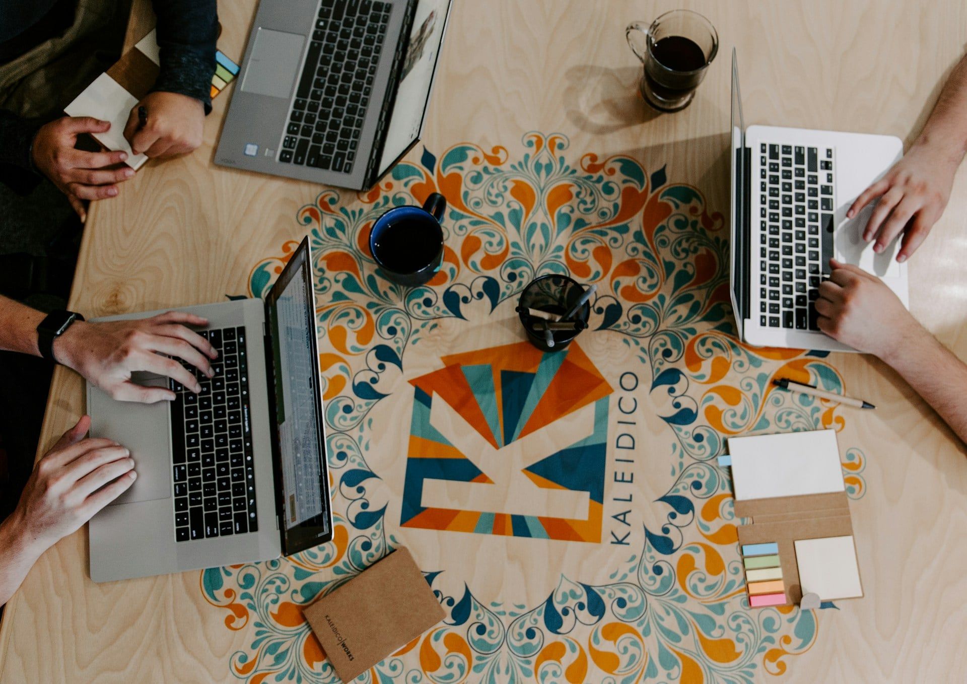 A top-down view of a desk with three people building a website on laptops
