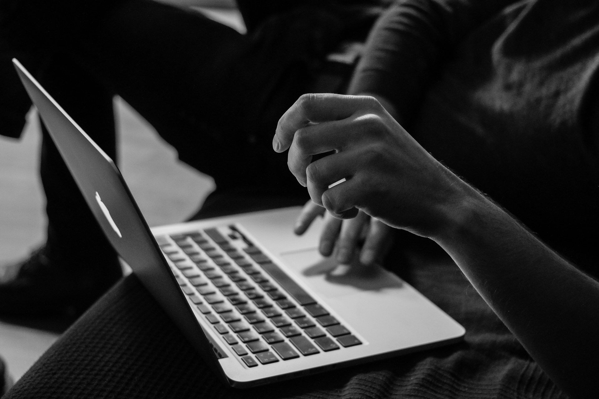 A black and white photo of someone searching online using a laptop and keywords
