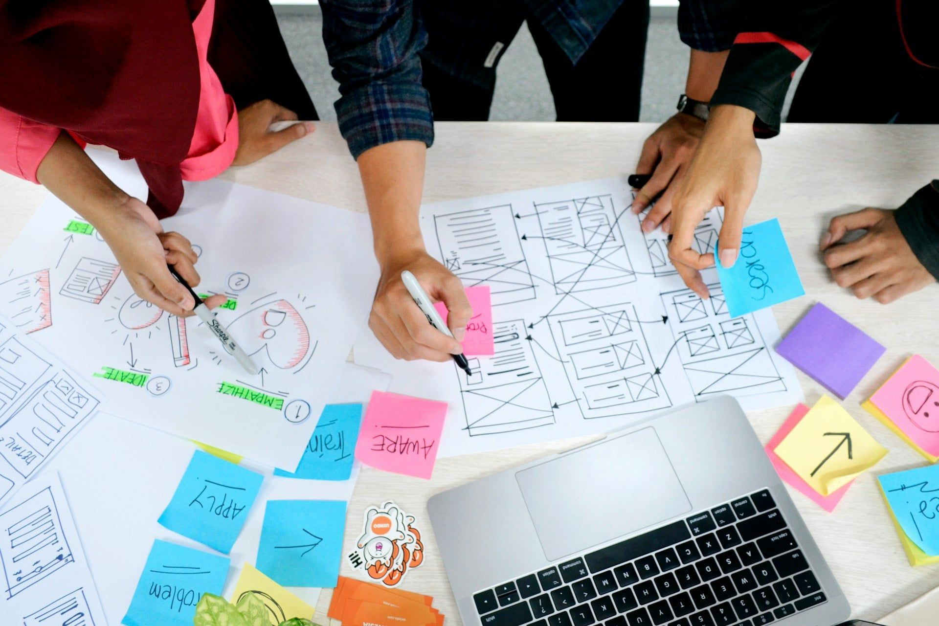 A desk with two people working on a website design using paper and pen